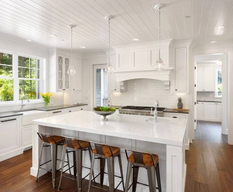 A kitchen with white cabinets and wooden floors.