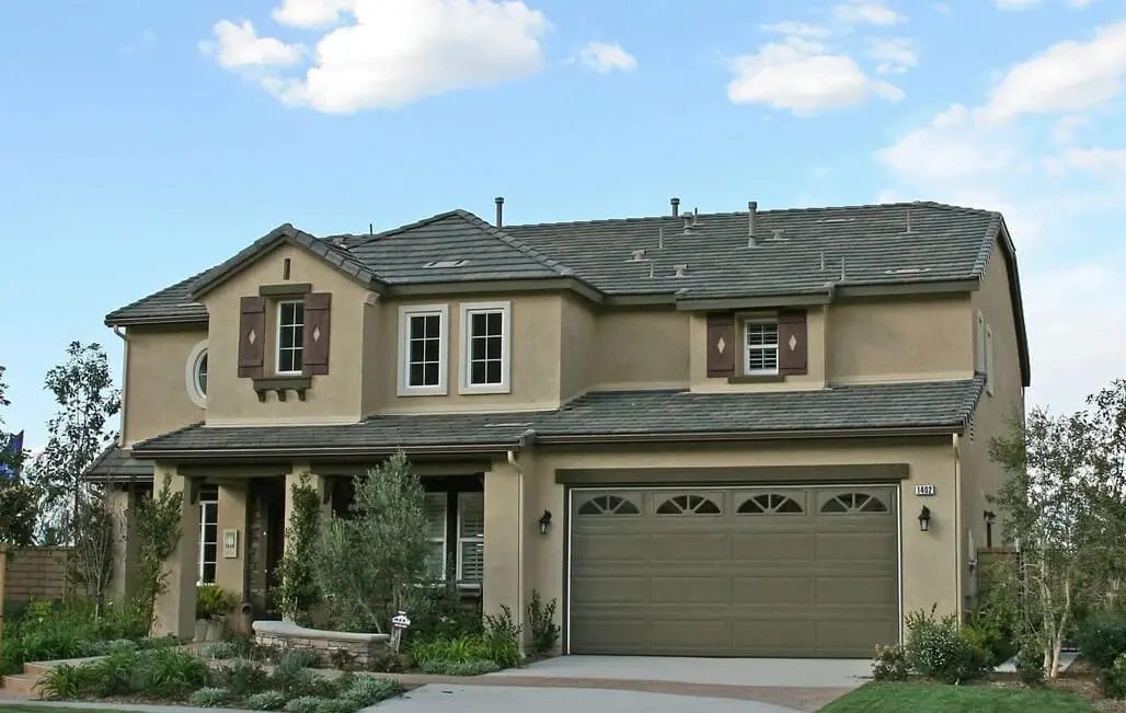 A large beige house with two garage doors.